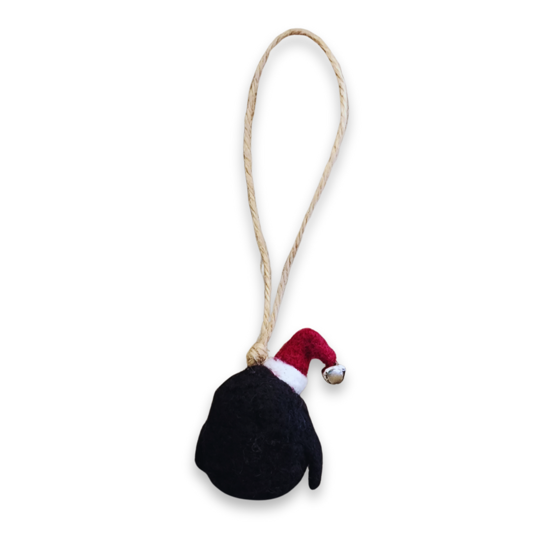 A back view of the penguin bobble, showing the attachment point of the jute string at the back of the hat and the black wool body.