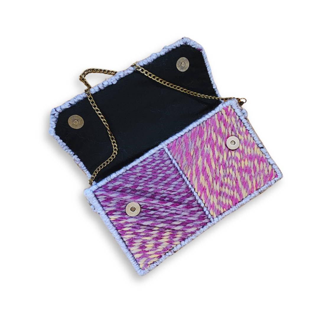An open clutch, showing the magnetic snap closure on the body of the bag and the black fabric lining underneath the flap.