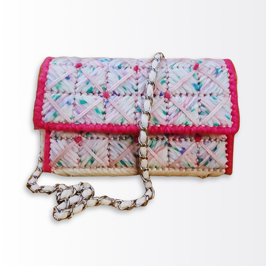 Front-facing view of the Strawberry Shortcake Bargello Mini Clutch highlighting the pink and white geometric checkered pattern, crisscross yarn overlay, and the silver chain strap with white yarn woven through the links.