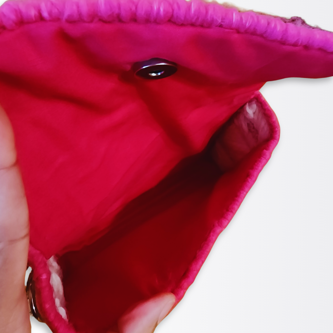 Interior view of the opened clutch revealing the vibrant hand-sewn hot pink cotton lining and the secure silver magnetic snap closure.