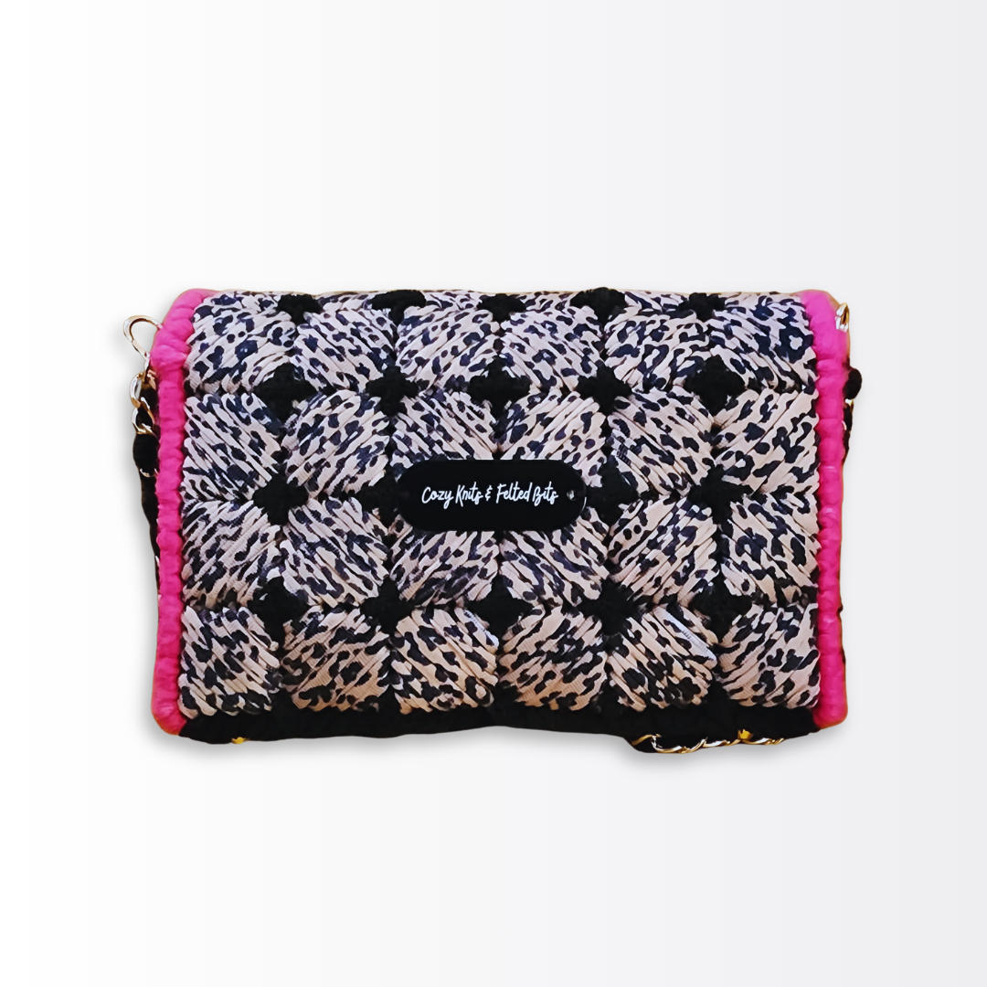 Back view of the hand-embroidered leopard clutch highlighting the seamless checkerboard pattern and the Cozy Knits & Felted Bits logo plate.