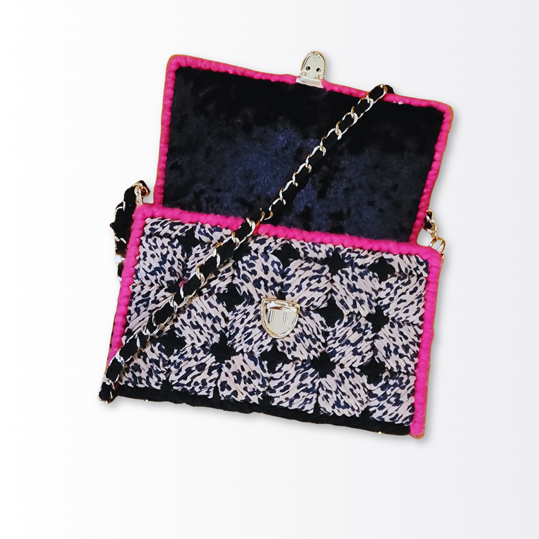Interior view of the opened leopard clutch revealing the hand-sewn velvet lining and the gold woven chain strap resting inside.