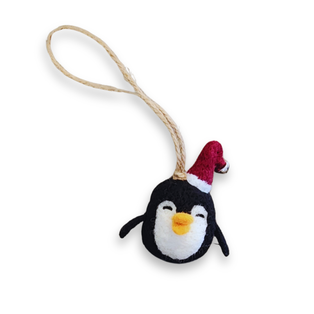 A cute, needle-felted penguin ornament with a red Santa hat and a gold bell, hanging from a natural jute string.