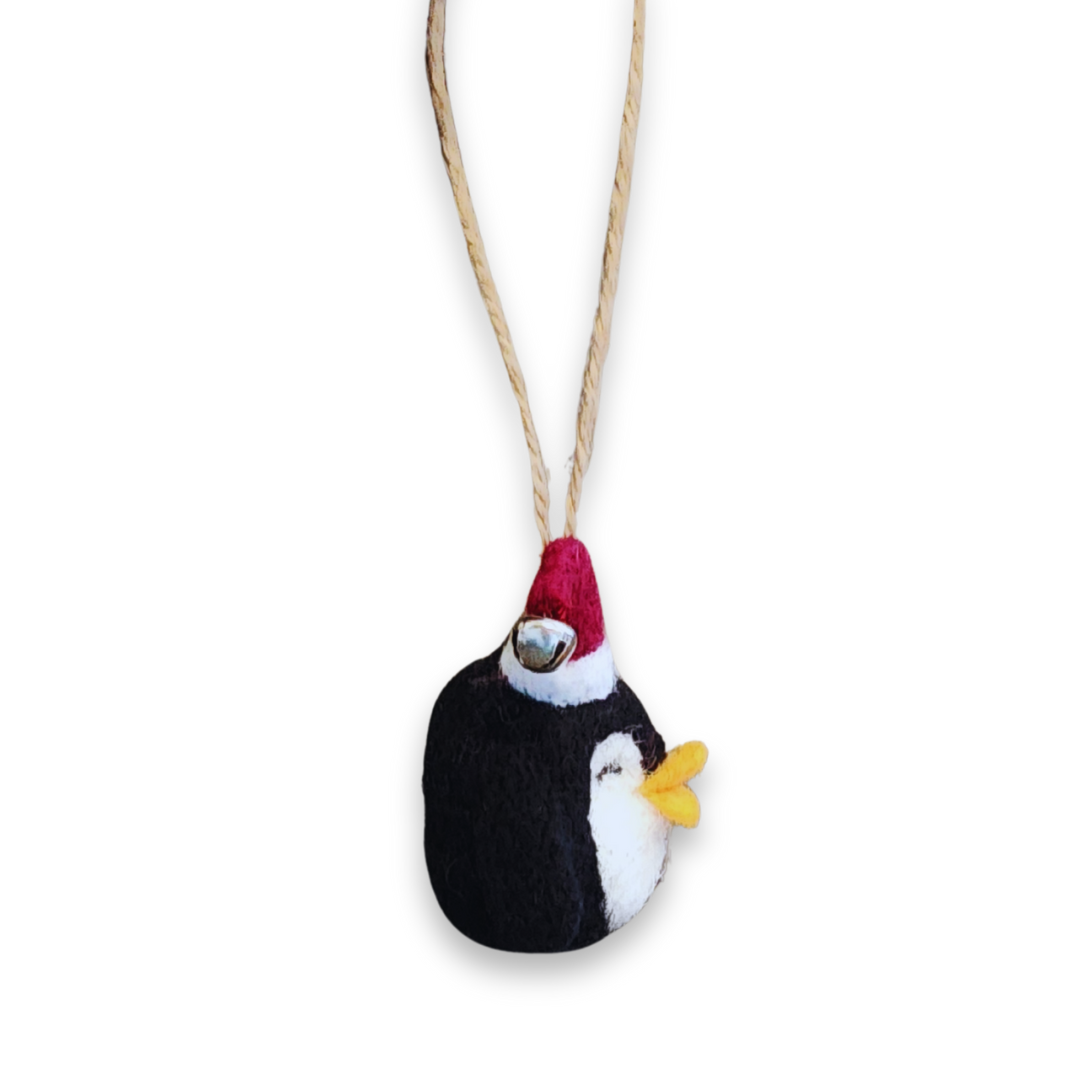 A side profile view of the penguin ornament hanging from the jute string, clearly showing the orange beak and the shape of the hat and bell.