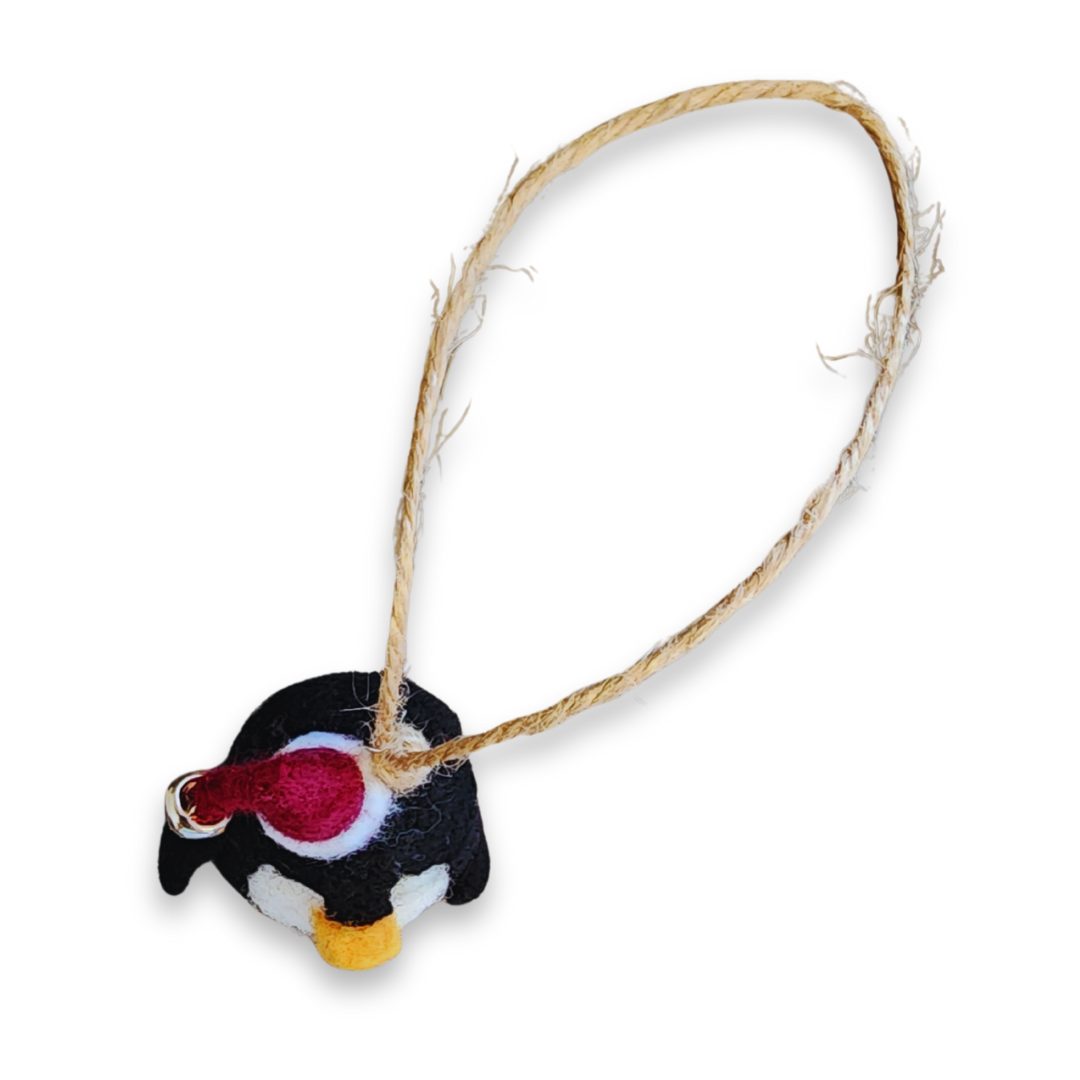 An overhead view of the penguin ornament, showing the full length of the jute string loop and the top of the penguin's head and hat.