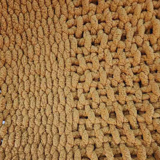 A close-up overhead view of a handmade hand-crocheted blanket, showing alternating rows of textured single stitch and basket weave stitch patterns in a sunset yellow color.