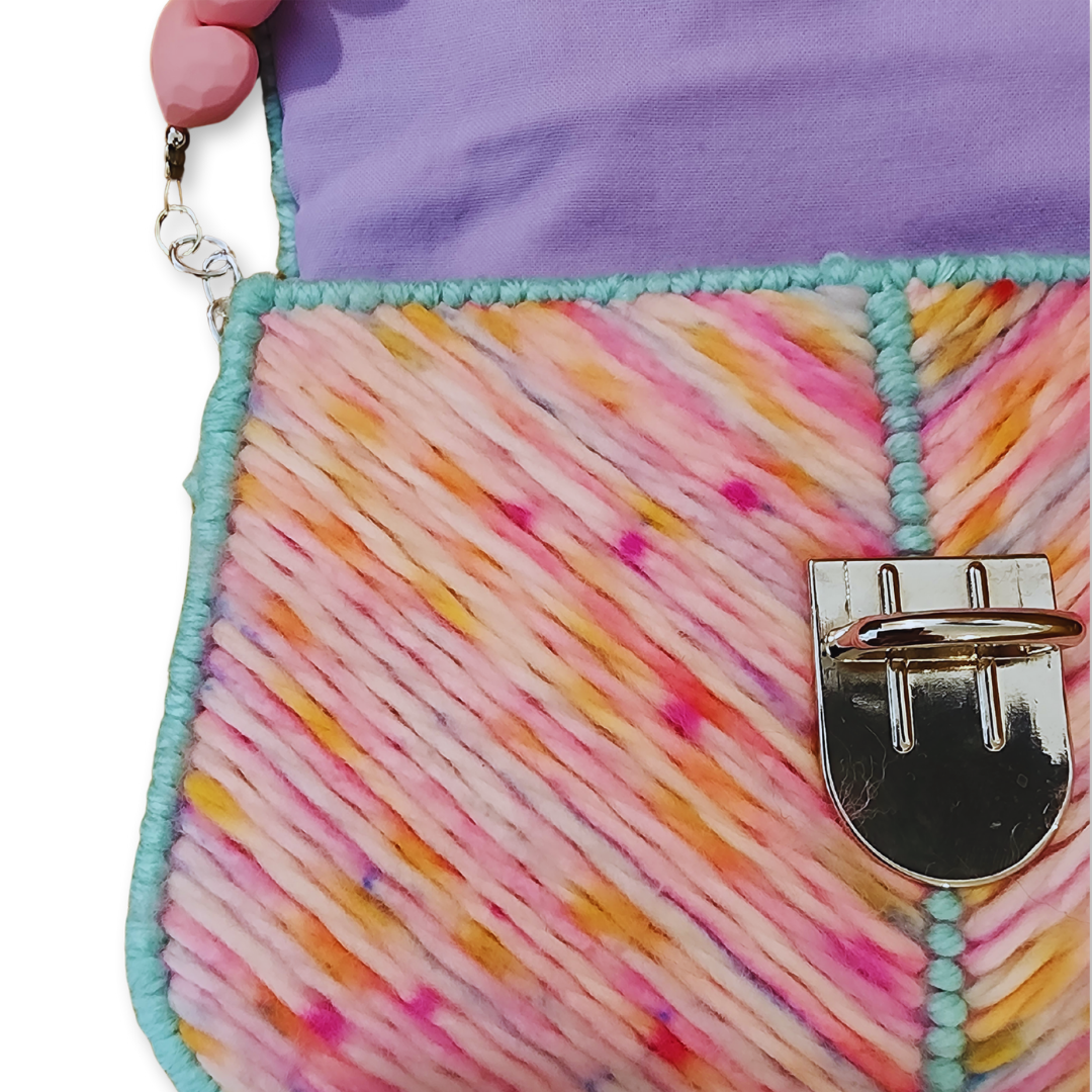 Extreme close-up of the hand-stitched chevron pattern and silver push-clasp, highlighting the dense texture and structural integrity of the fiber art.