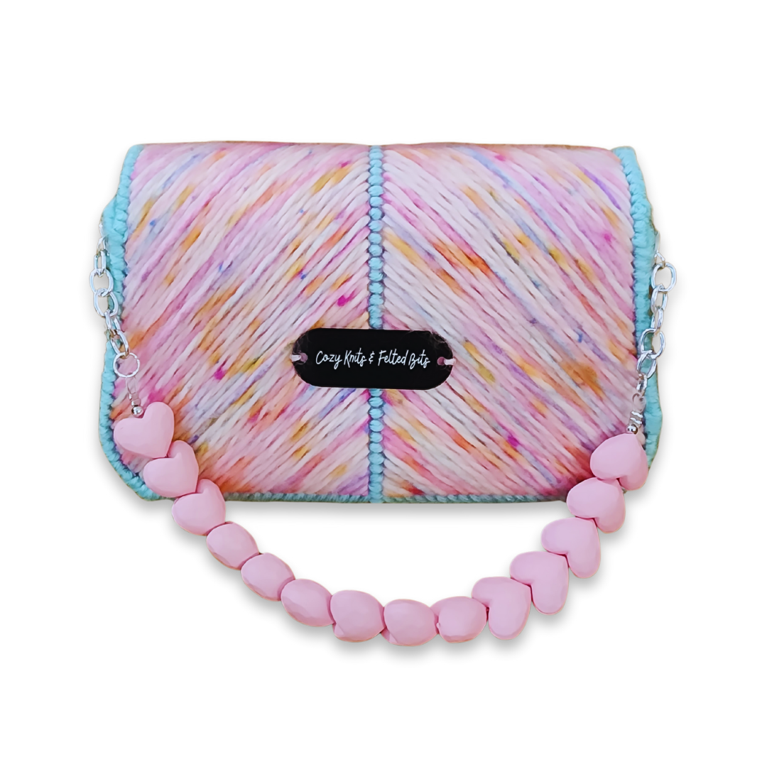 Back view of the clutch featuring the "Cozy Knits & Felted Bits" logo plate and the seamless continuation of the multicolored chevron pattern.