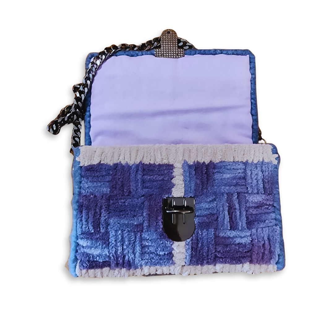 The Galaxy Checker Mini Clutch opened to reveal a hand-sewn light purple lining. This view highlights the bespoke finishing of the internal frame and the plush texture of the blue and purple fluffy yarn.
