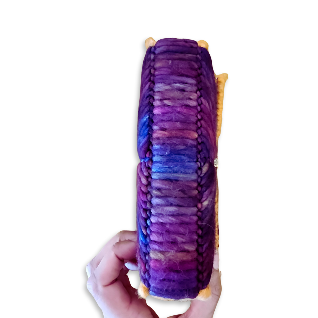 Bottom view of the structured fiber bag base, demonstrating the durable embroidery technique and high-density stitching that allows the clutch to stand upright.