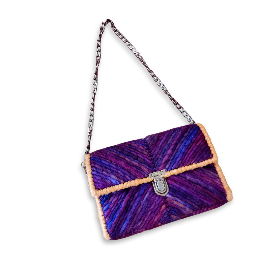 Angled front view of the structured mini clutch with the bronze chain strap extended, showcasing the sharp silhouette and vibrant purple ombre pattern.