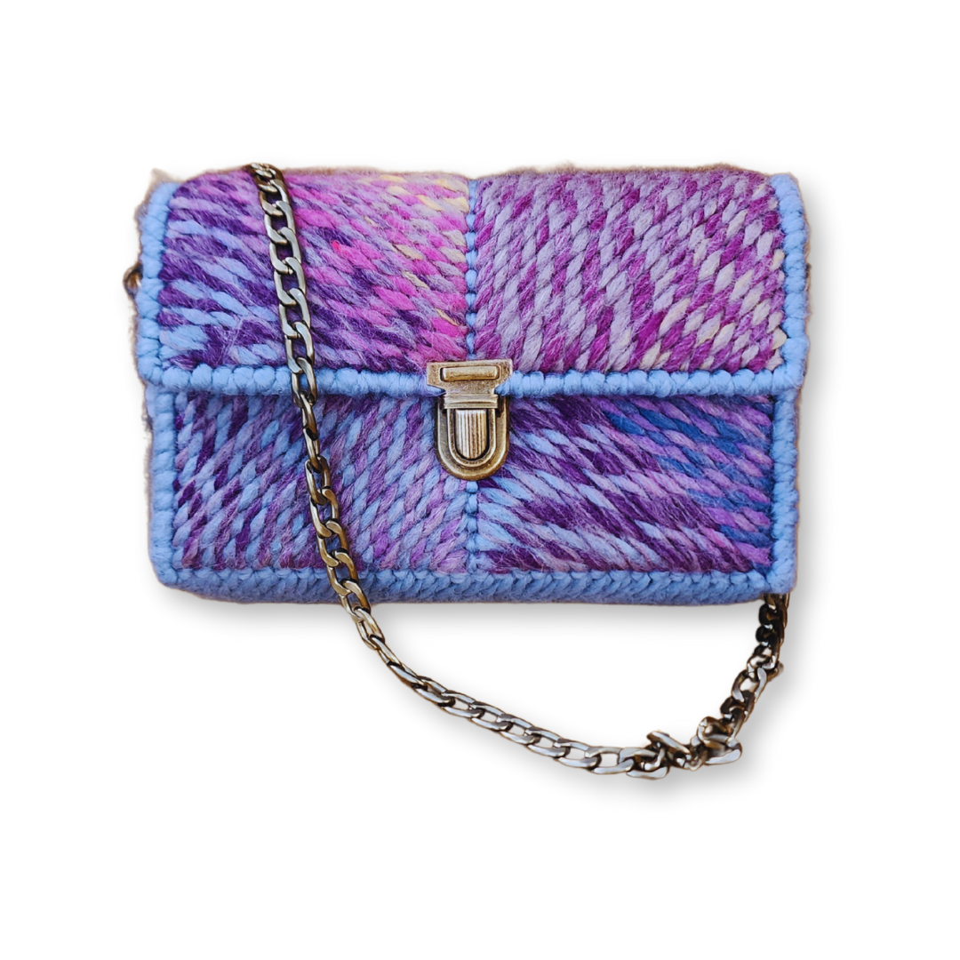 Front view of the Purple Ombre Patchwork Mini Clutch featuring a chevron stitch design in a vibrant purple, blue, and pink ombre yarn. The design includes greyish-blue accents and an ornate bronze push-lock clasp.