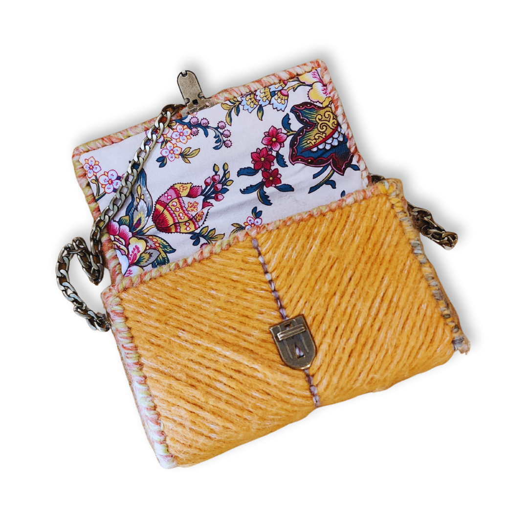 Interior view of the Golden Honey Mini Clutch opened to reveal a hand-sewn cotton lining with a vibrant oriental floral design. The image highlights the bespoke finishing and the secure attachment of the bronze hardware.