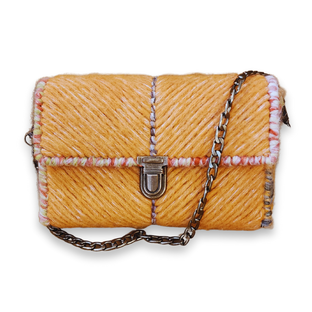 Full front view of the structured fiber bag with the 23-inch bronze chain strap draped across the exterior. This angle emphasizes the durable embroidery technique and the rich, golden hue of the soft yarn.