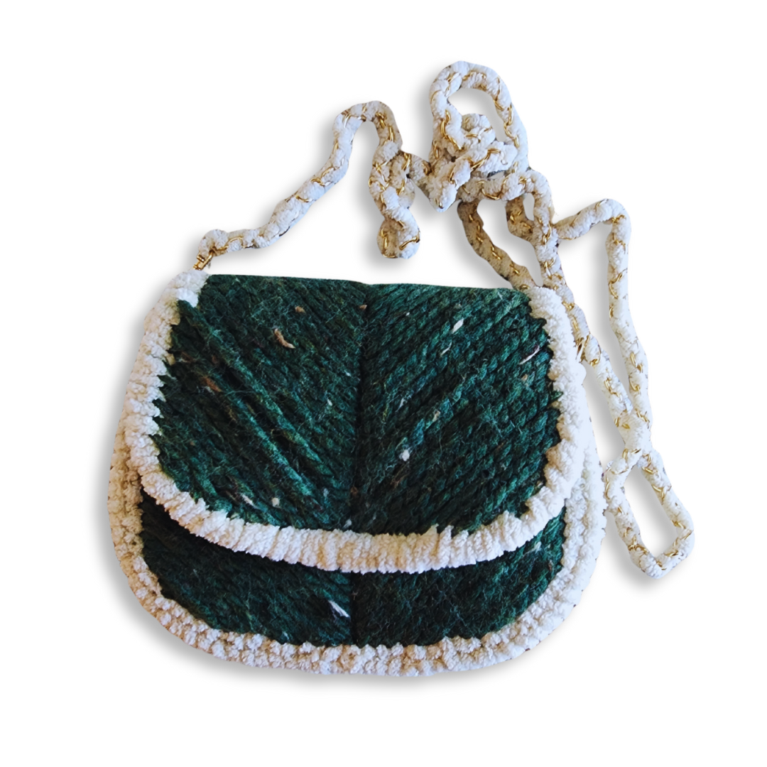 A front view of the saddlebag, emphasizing the rounded flap and the rich, speckled green yarn texture against the plush white chenille trim and woven strap
