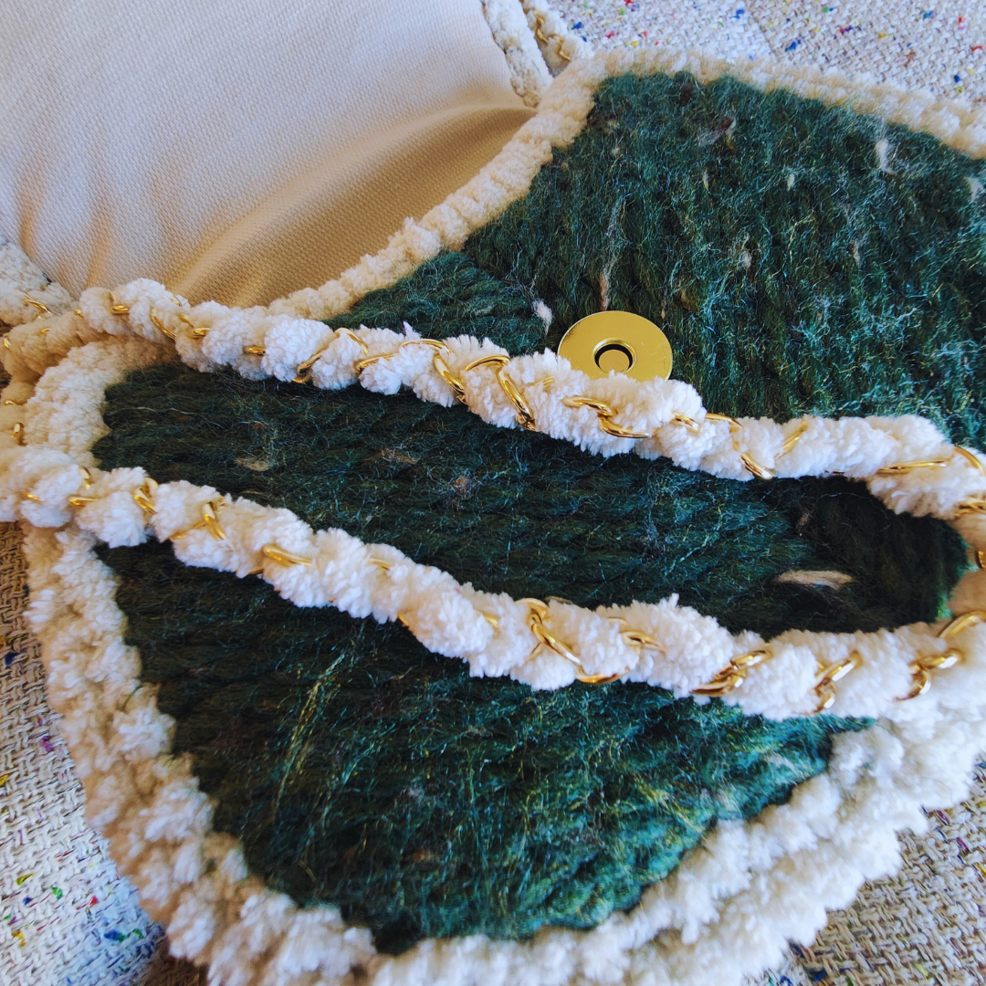 An extreme close-up of the bag's textured flap, showing the gold magnetic clasp and the woven strap, which is a gold chain wrapped in white chenille yarn.