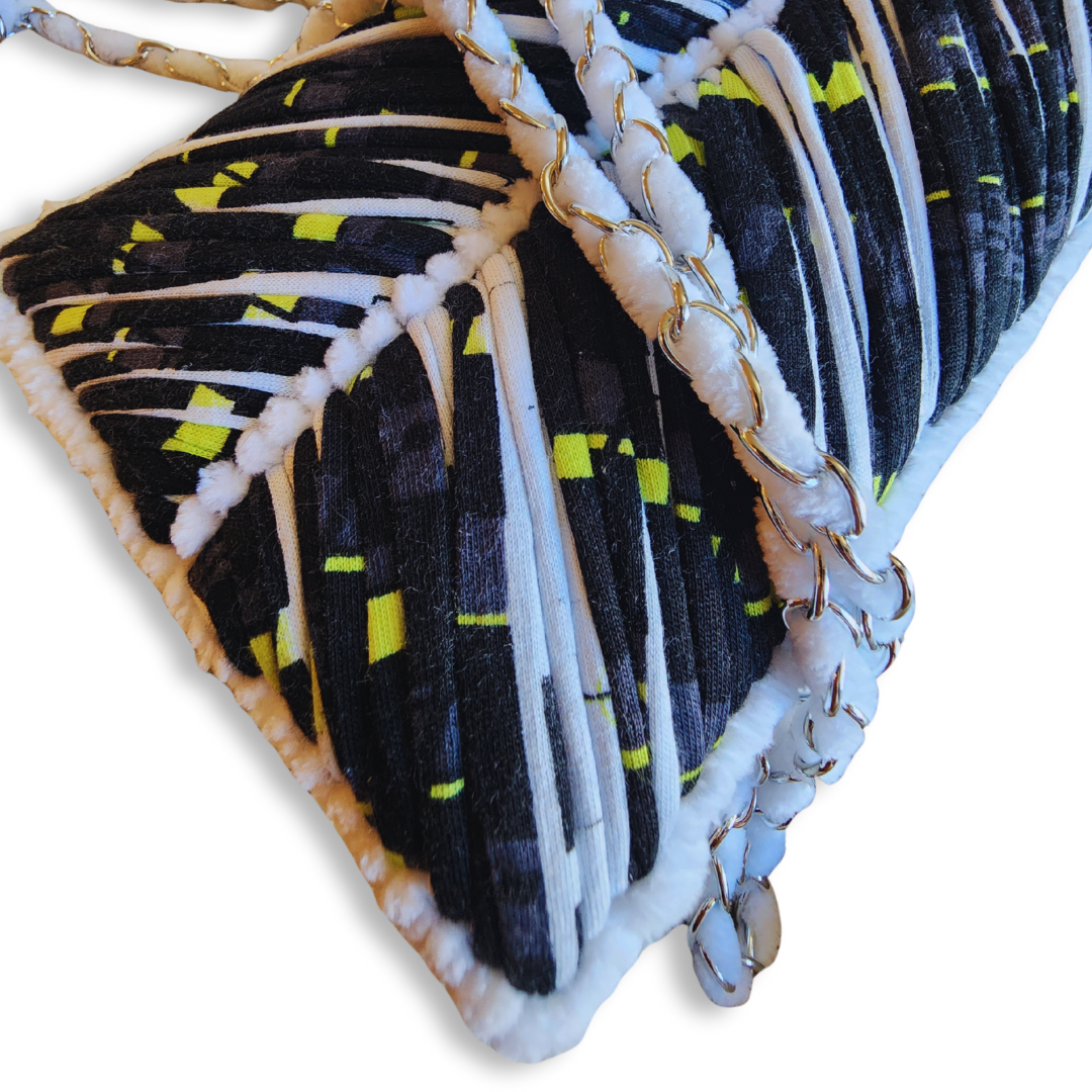 A close-up shot of the corner of the phone purse, highlighting the black, white, and neon yellow embroidery, the white chenille fuzzy edge, and the silver metal chain detail.