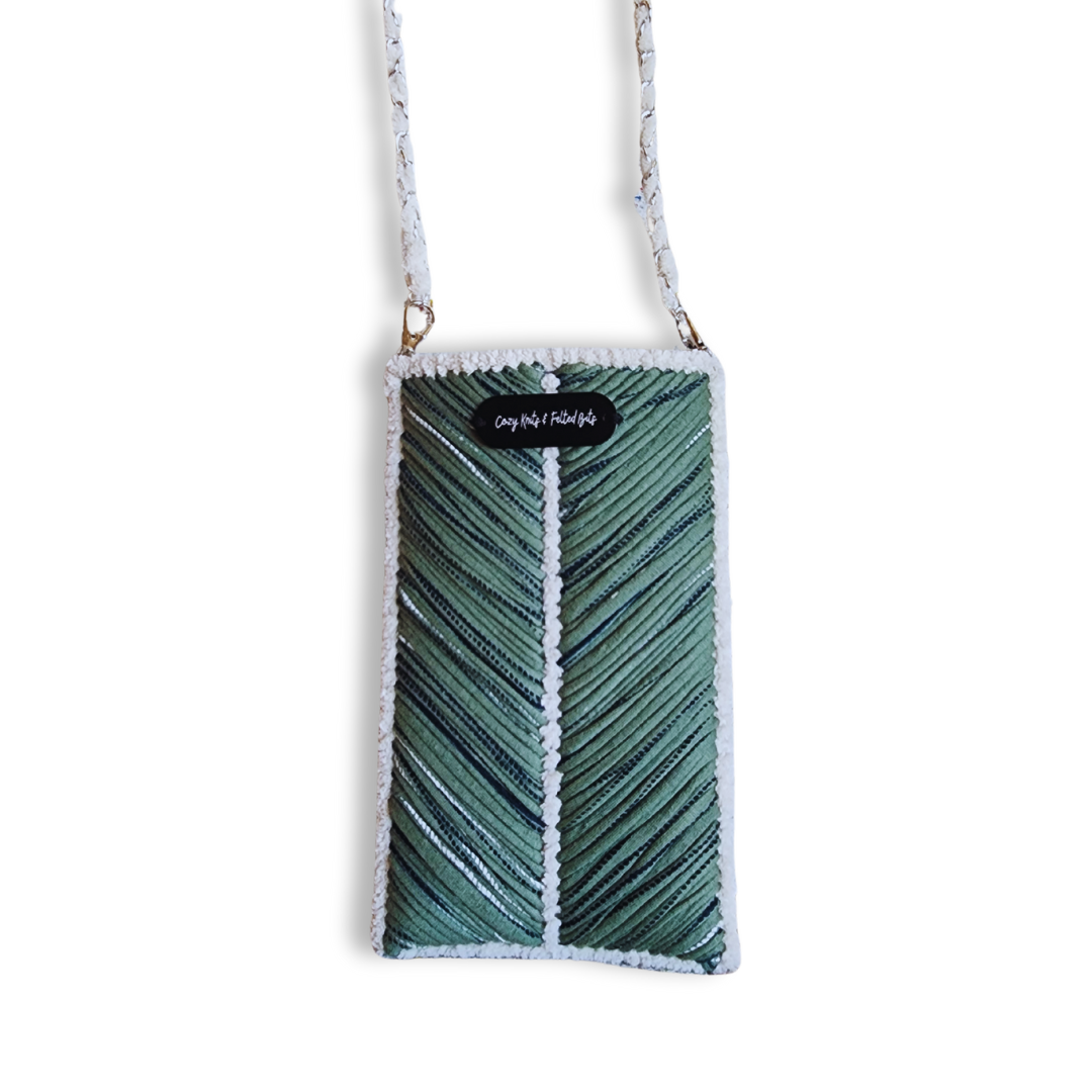 A full view of the olive green phone purse, featuring a central chevron pattern and a white woven chain strap. A small "Cozy Knits & Felted Bits" tag is visible at the top.