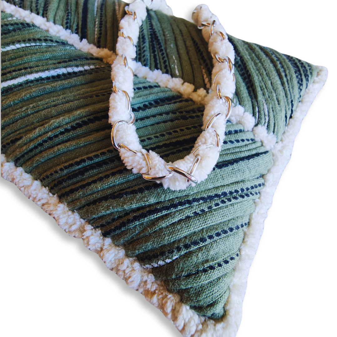 A close-up shot of the corner of the olive green phone purse, highlighting the fuzzy white chenille trim and the woven metal chain strap resting on the bag.