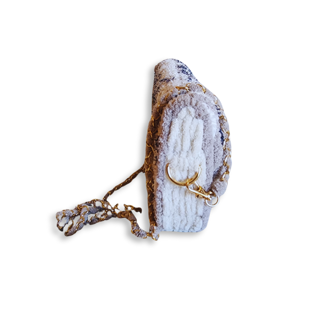 A side view of the saddlebag, emphasizing its compact, rounded shape and the woven chain strap detail.