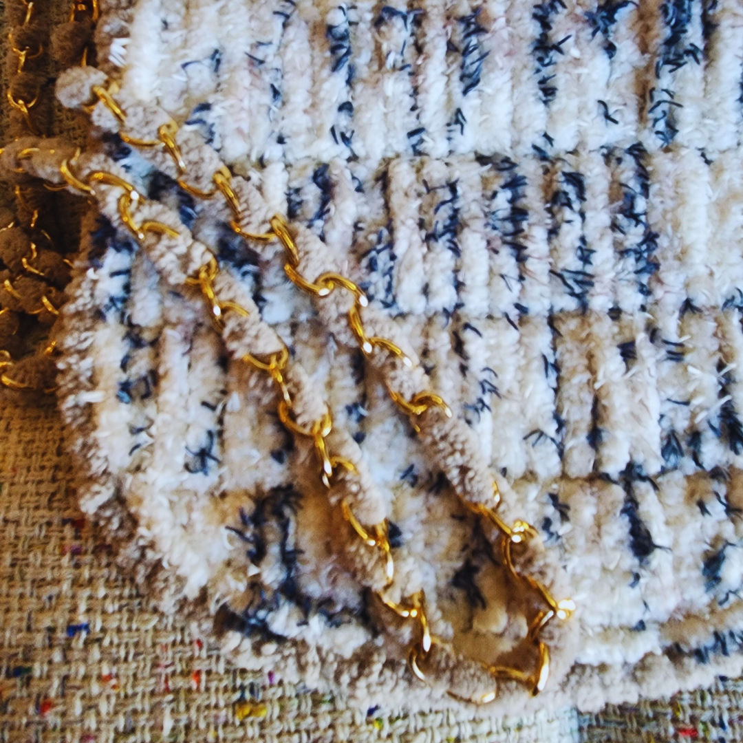 An extreme close-up of the bag's textured yarn and the gold metal chain strap with beige yarn woven through it, highlighting the seaside blend color.