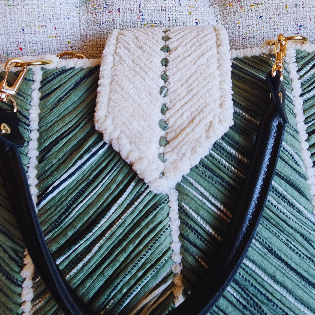 A close-up of the tote bag's magnetic closure flap, which is made of thick white chenille with green stitching, contrasted against the green chevron pattern of the bag's body.