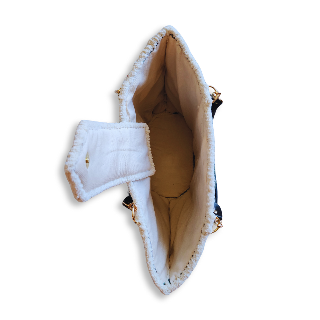 An overhead view looking inside the angled tote bag, showing the deep interior, the cream-colored lining, and the soft, white chenille trim along the top opening.