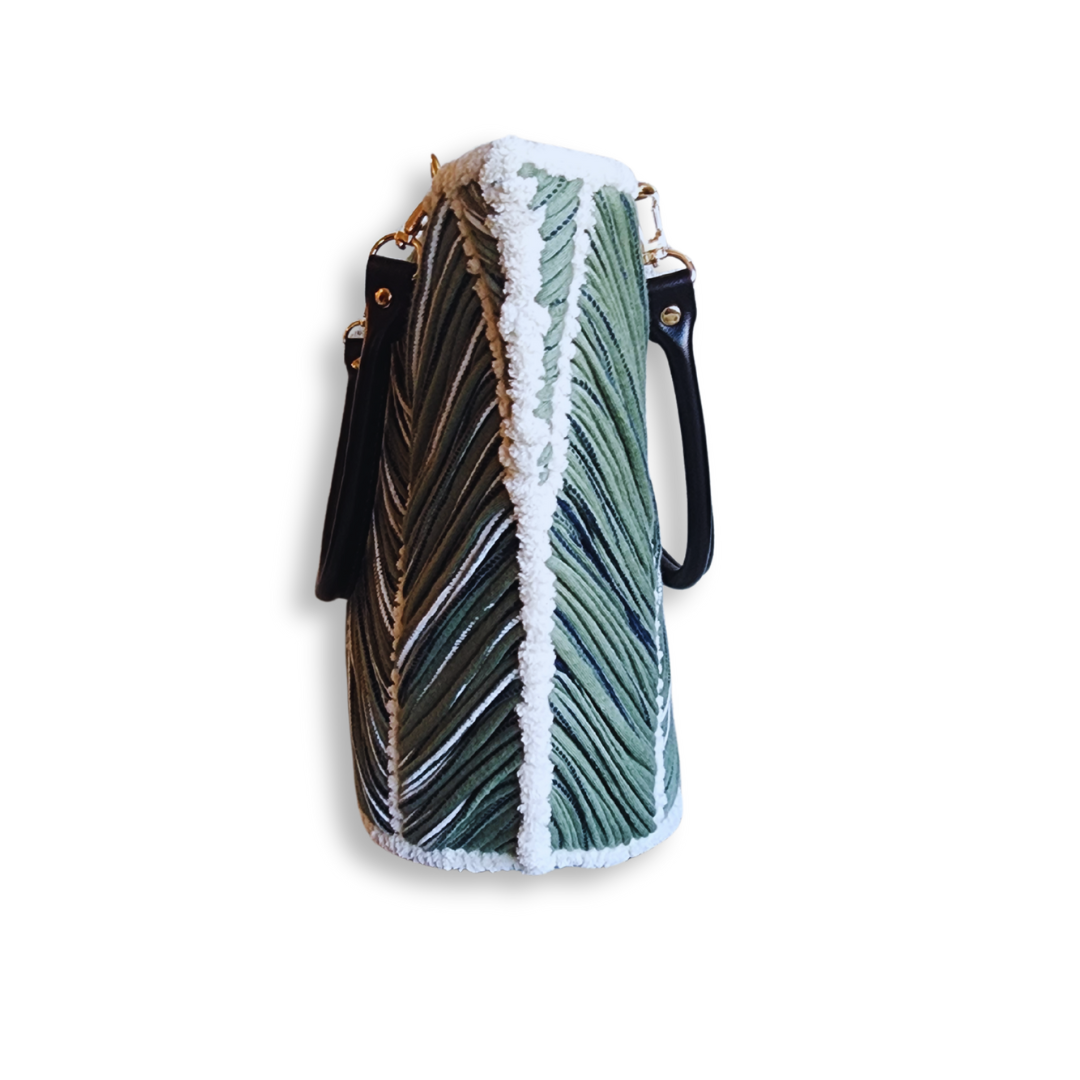 A side view of the tote bag, highlighting its tall, angled shape and the vertical chevron pattern, with the black leather strap visible on the side.