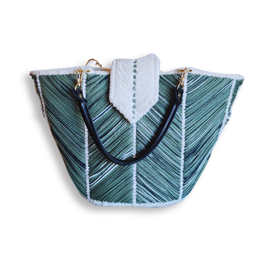 A front view of the angled tote bag, showcasing the green chevron embroidery, the black leather straps, and the white chenille closure flap.