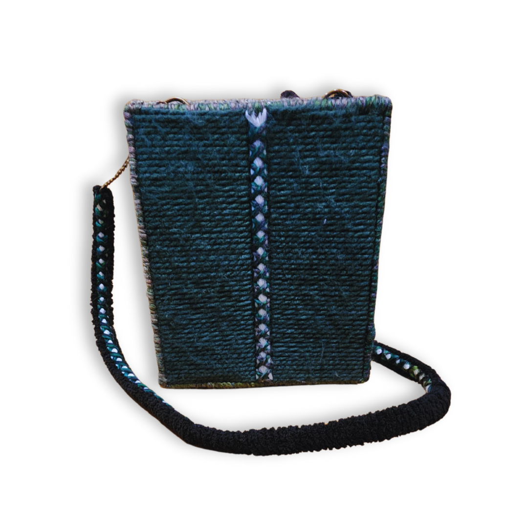 A structured, rectangular embroidered crossbody bag in deep forest green, showing the side profile and the custom handmade shoulder strap with bronze chain accents.