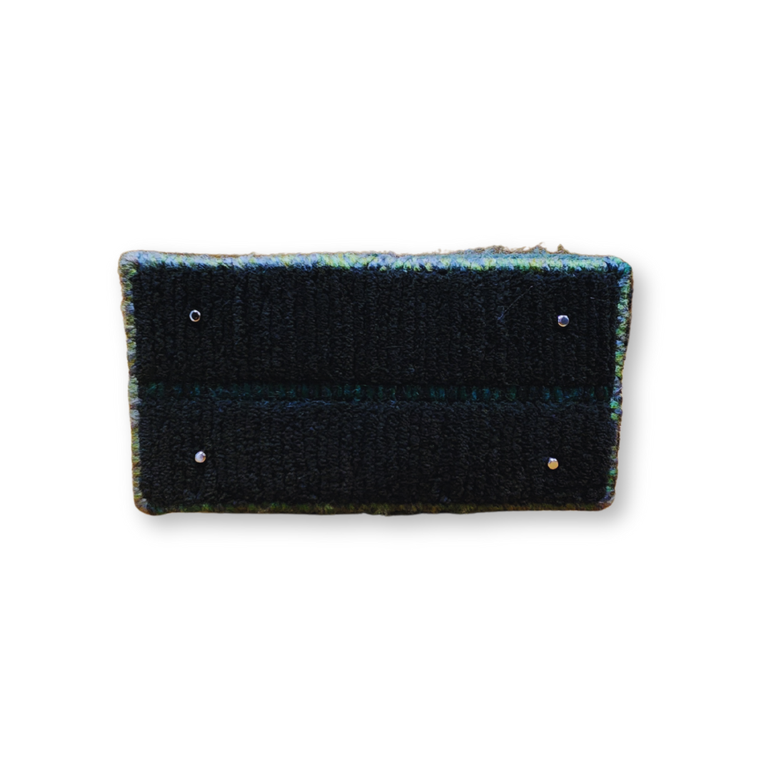 The bottom of the bag, showing the solid structure, the dark yarn base, and the four protective bronze purse feet.