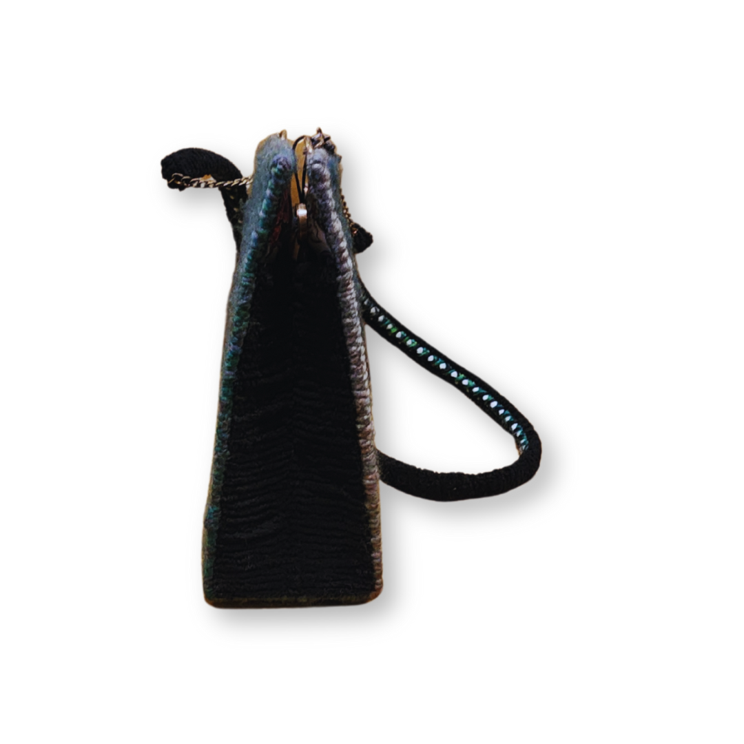 A side view of the structured crossbody bag, showing its 3.5" depth and the bronze hardware near the top opening.