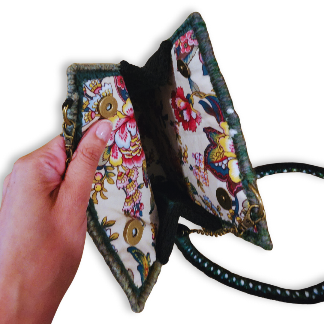 A view of the open bag, showcasing the intricate multicolor floral lining and the bronze magnetic snap closure hardware.