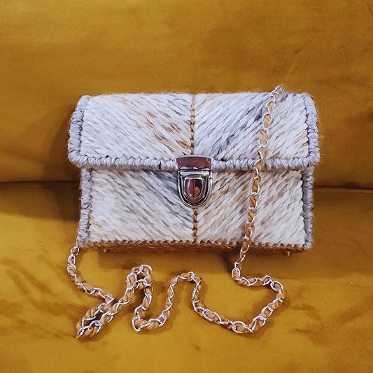 Front view of the Desert Stone Mini Shoulder bag featuring a grey and caramel ombre chevron yarn pattern and a silver push-lock clasp, resting on a mustard yellow surface.