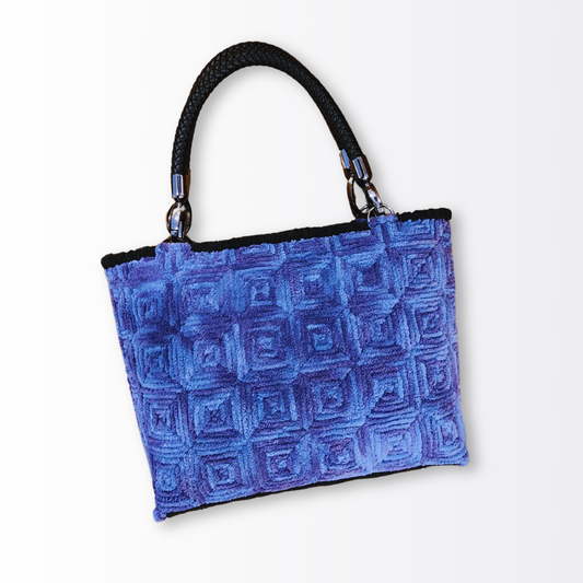 Angled front view emphasizing the contrast between the soft lavender fiber and the industrial black braided leather handle with gunmetal attachments.