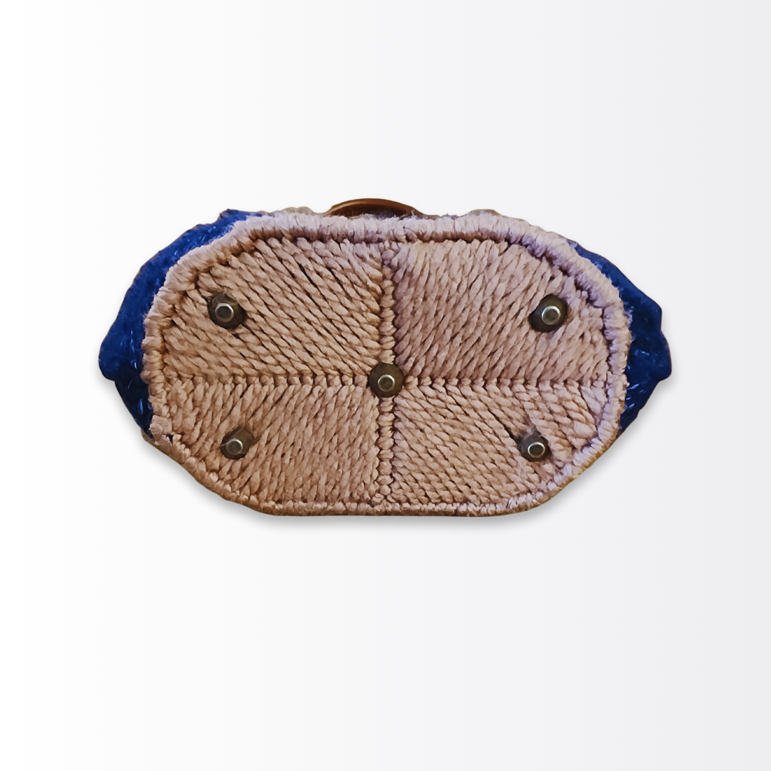 Bottom view of the structured navy tote base showcasing the caramel yarn accents and five protective bronze purse feet to safeguard the artisan design.
