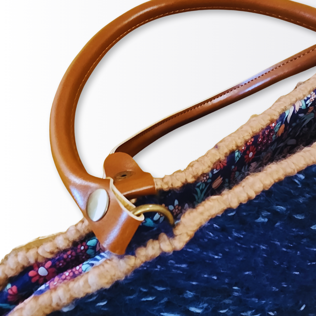 Macro shot focusing on the caramel leather strap attachment and the intricate hand-stitching along the scalloped top edge and bronze hardware.