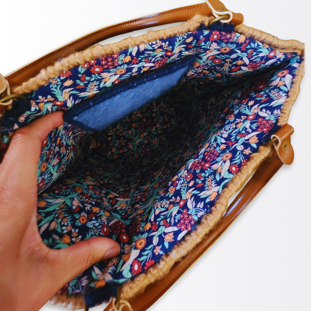 Top-down view into the spacious tote interior highlighting the hand-sewn multicolored floral lining and the dedicated internal pocket with light blue yarn detailing.