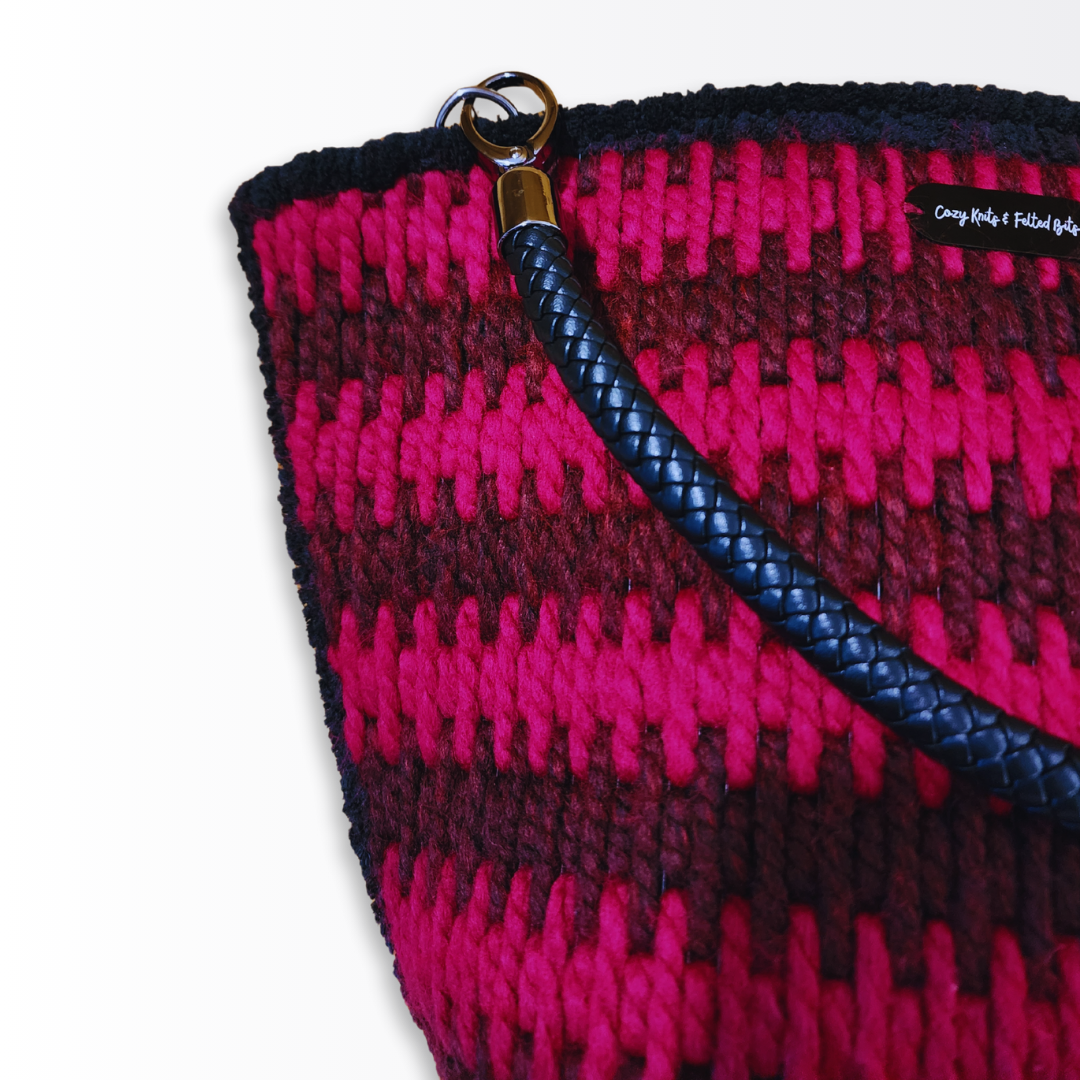 Close-up of the braided leather handle and gunmetal hardware against the crimson and mahogany embroidery.