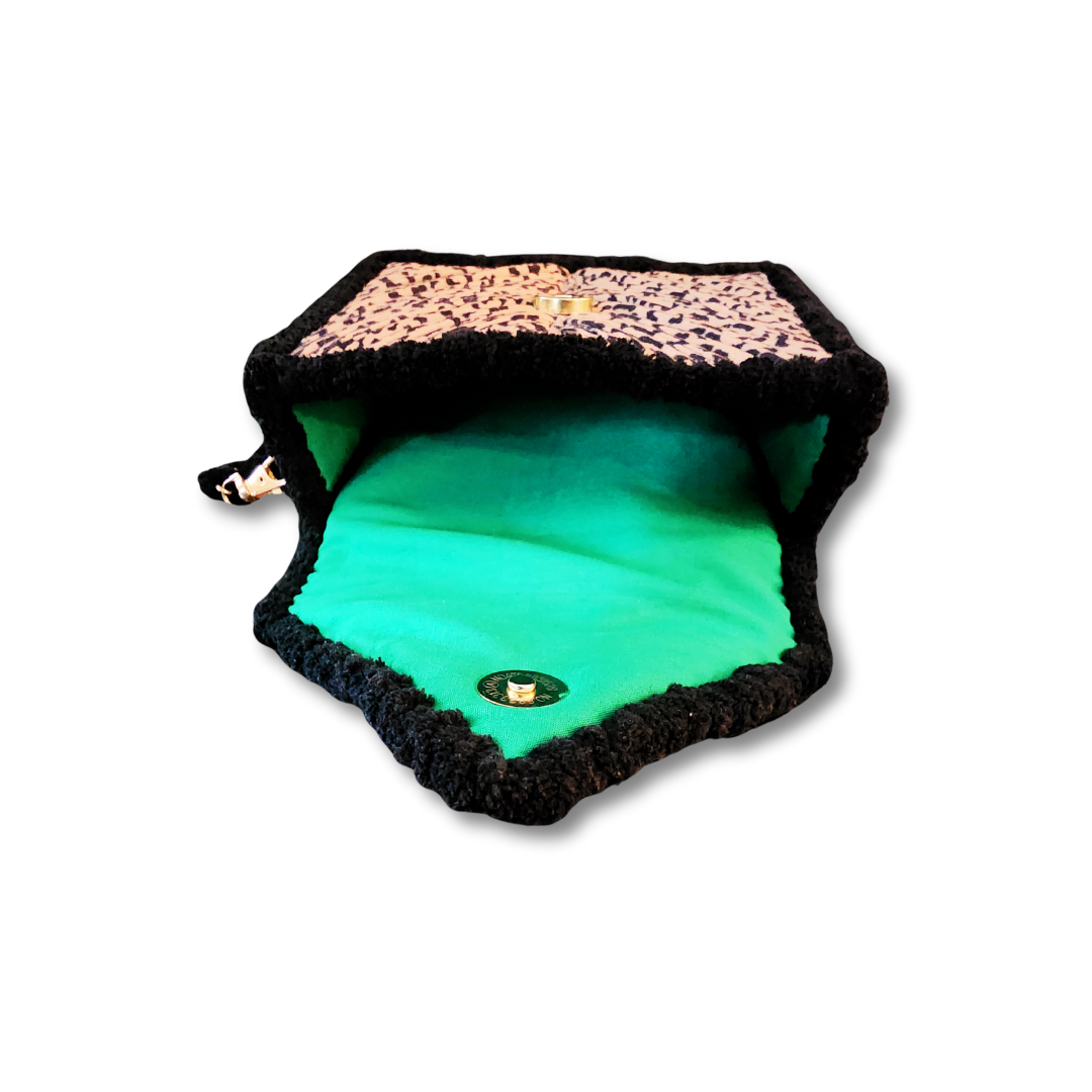 The small clutch is shown fully open, displaying the vibrant neon green lining inside the black chenille border and the gold magnetic clasp on the flap.