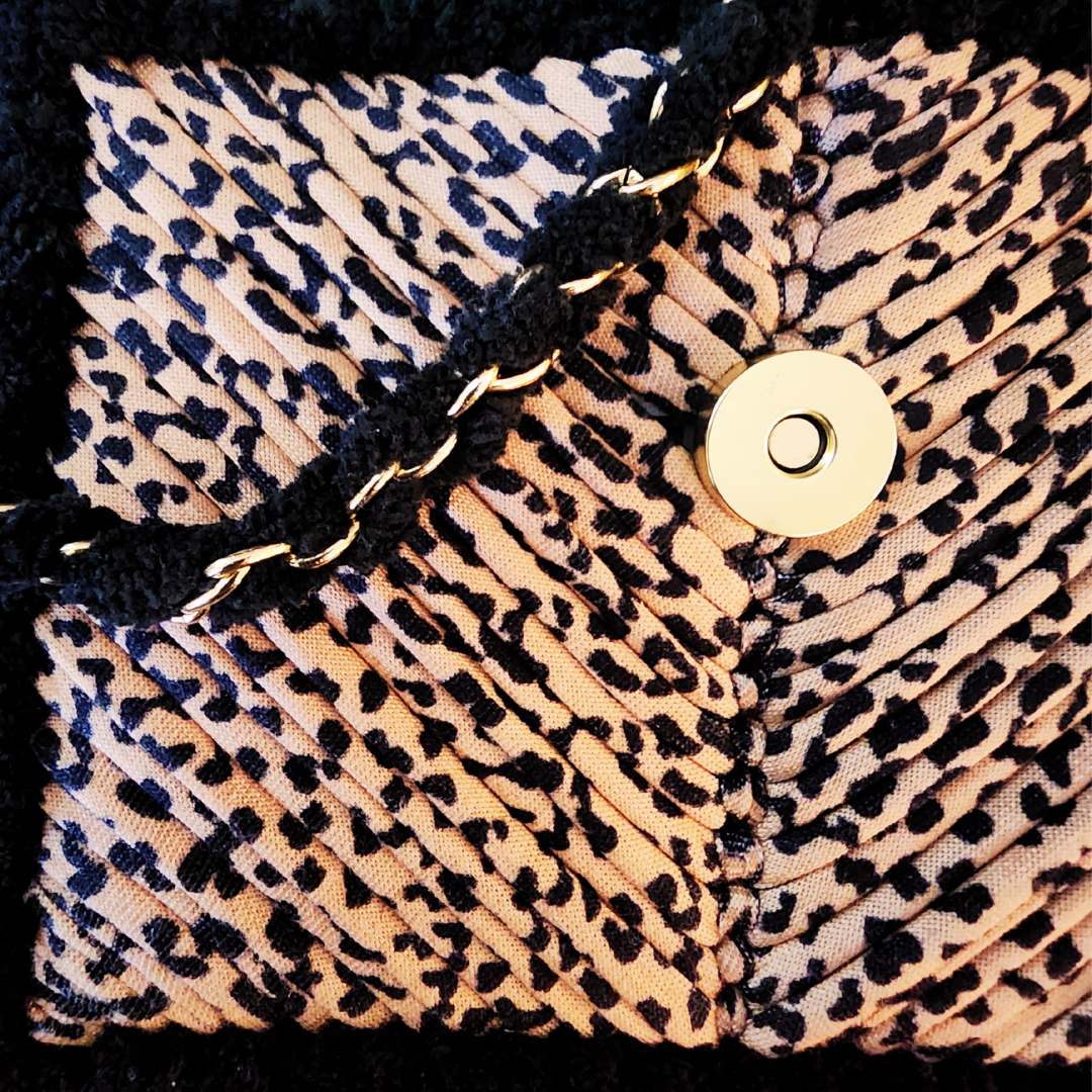 A close-up shot of the Leopard Print embroidery texture, the black chenille trim, and the round gold magnetic clasp closure detail.