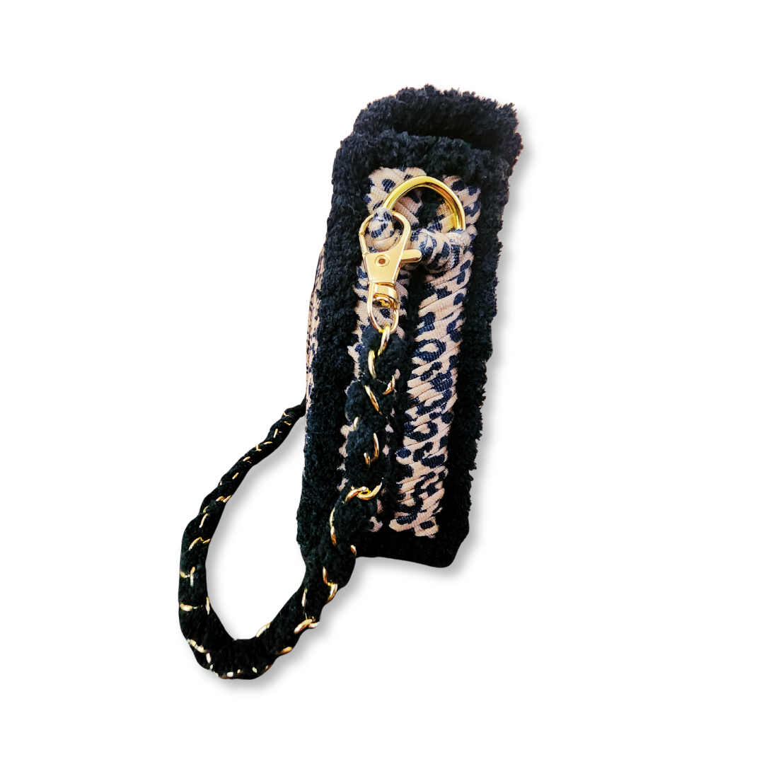A side view of the clutch, highlighting the black chenille border and the gold lobster claw clasp where the black and gold woven chain strap attaches.