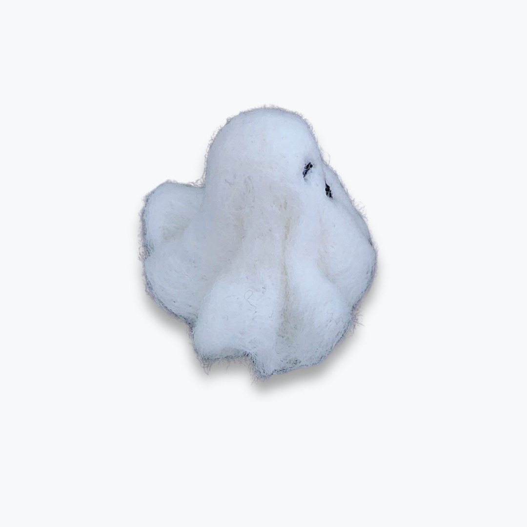 A small handmade felted ghost figurine with a wide black smiling mouth and small eyes, viewed from a high angle against a plain white background.