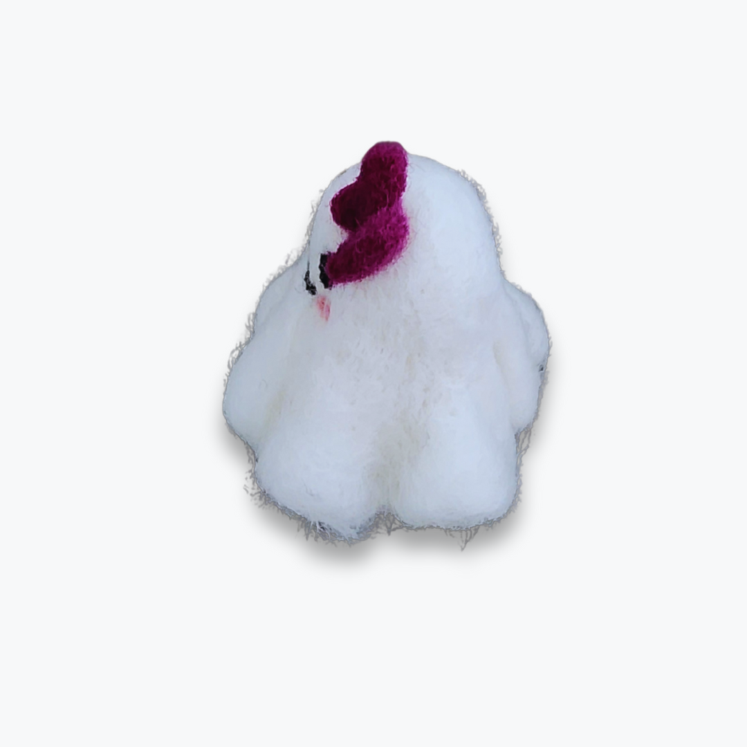 A small handmade felted ghost figurine with a purple bow, a cute smiling mouth, and pink cheeks, viewed from a high angle against a plain white background.