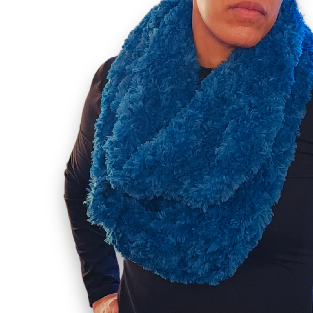 A close-up view of the wide marine blue faux fur infinity scarf, looped twice and showcasing the plush, textured yarn.