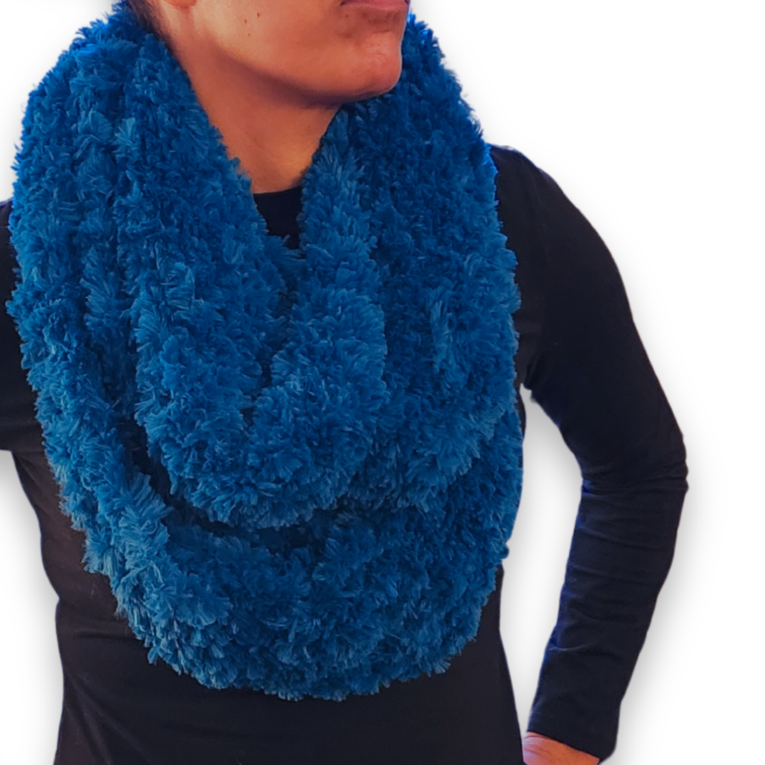 A person models the wide marine blue faux fur infinity scarf, worn in a double loop.