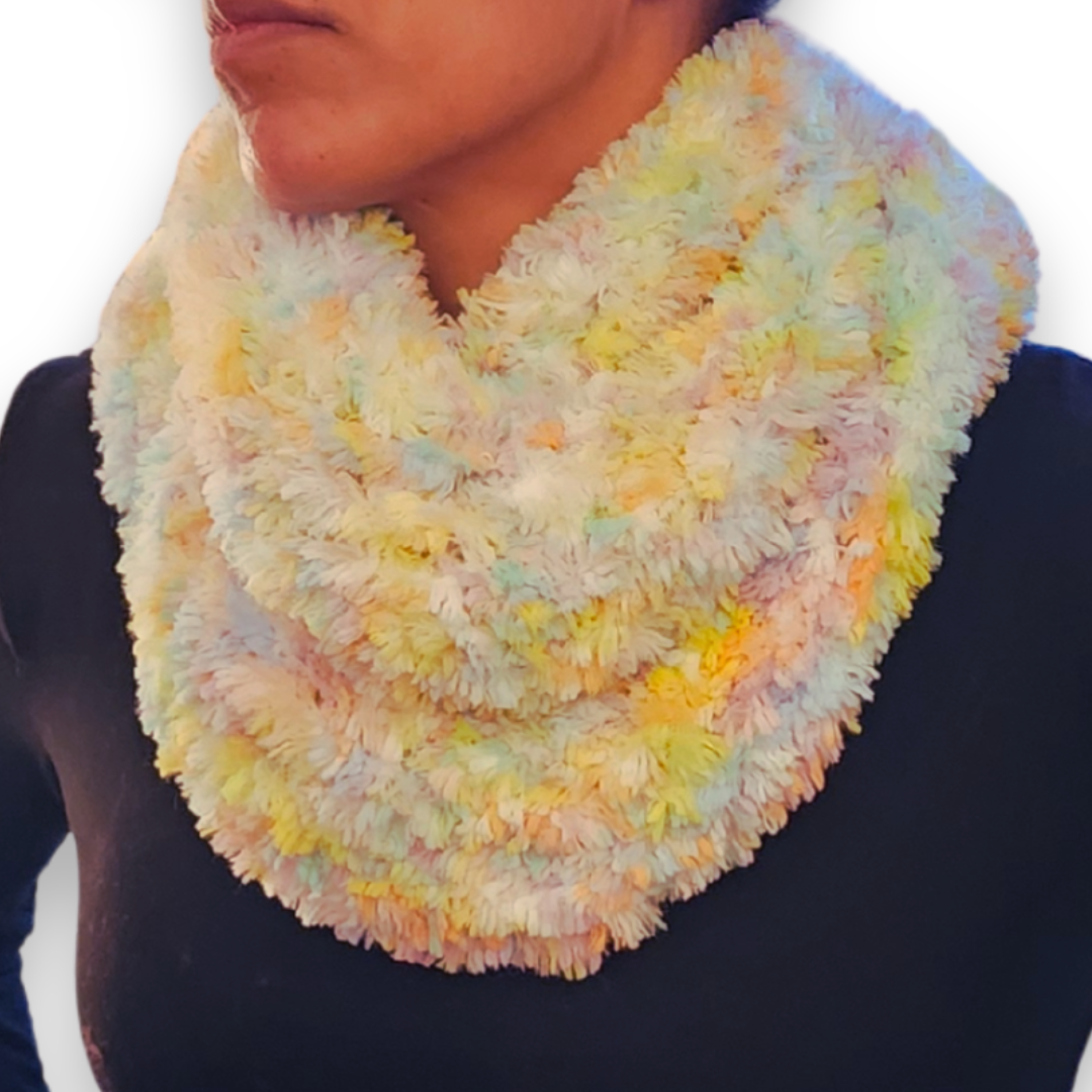 A person models a skinny, brightly colored "sprinkles" faux fur infinity scarf (featuring yellow, green, pink, and white) looped around the neck.