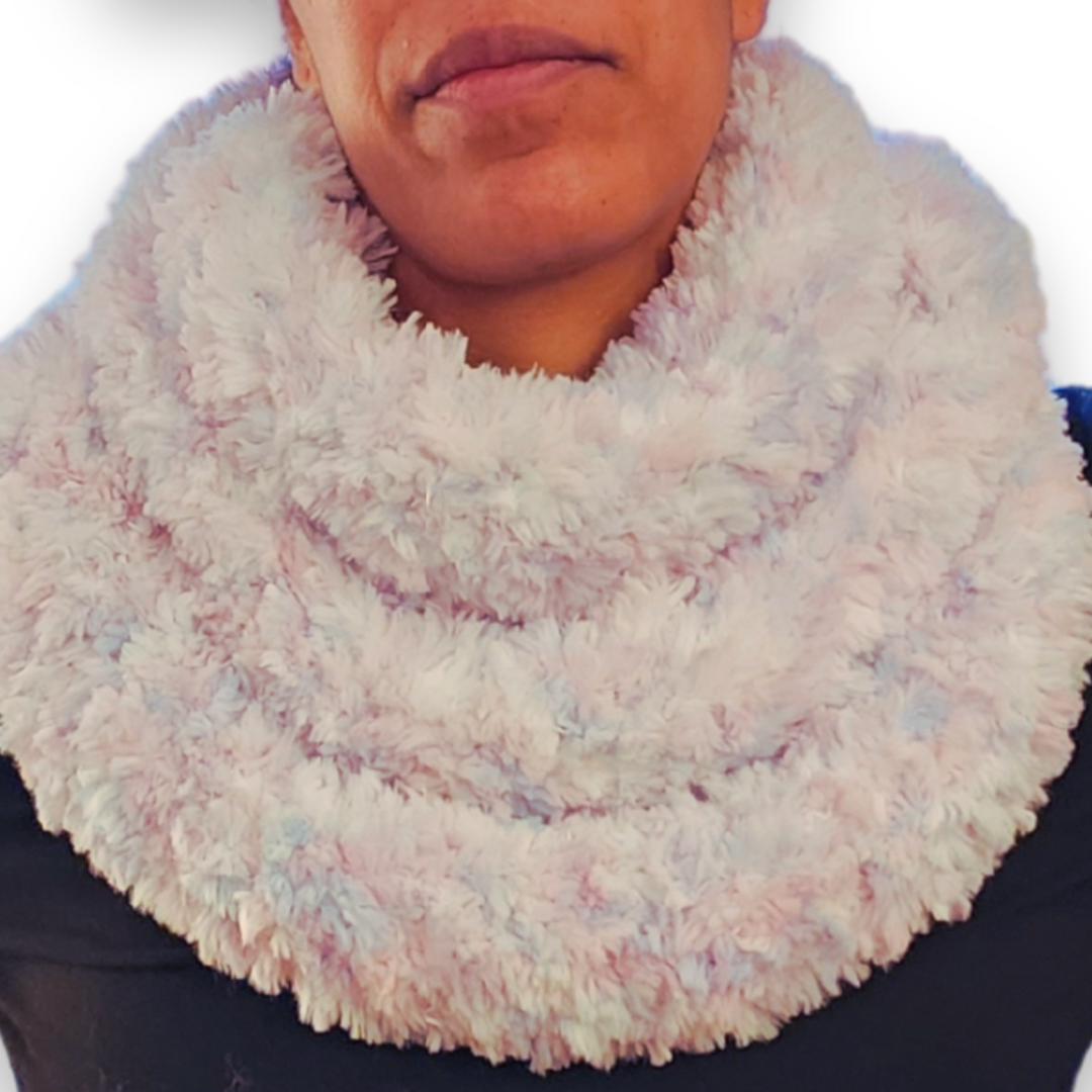 A person models a skinny, multi-colored "unicorn" faux fur infinity scarf (featuring pastel pink and blue) looped high around the neck.