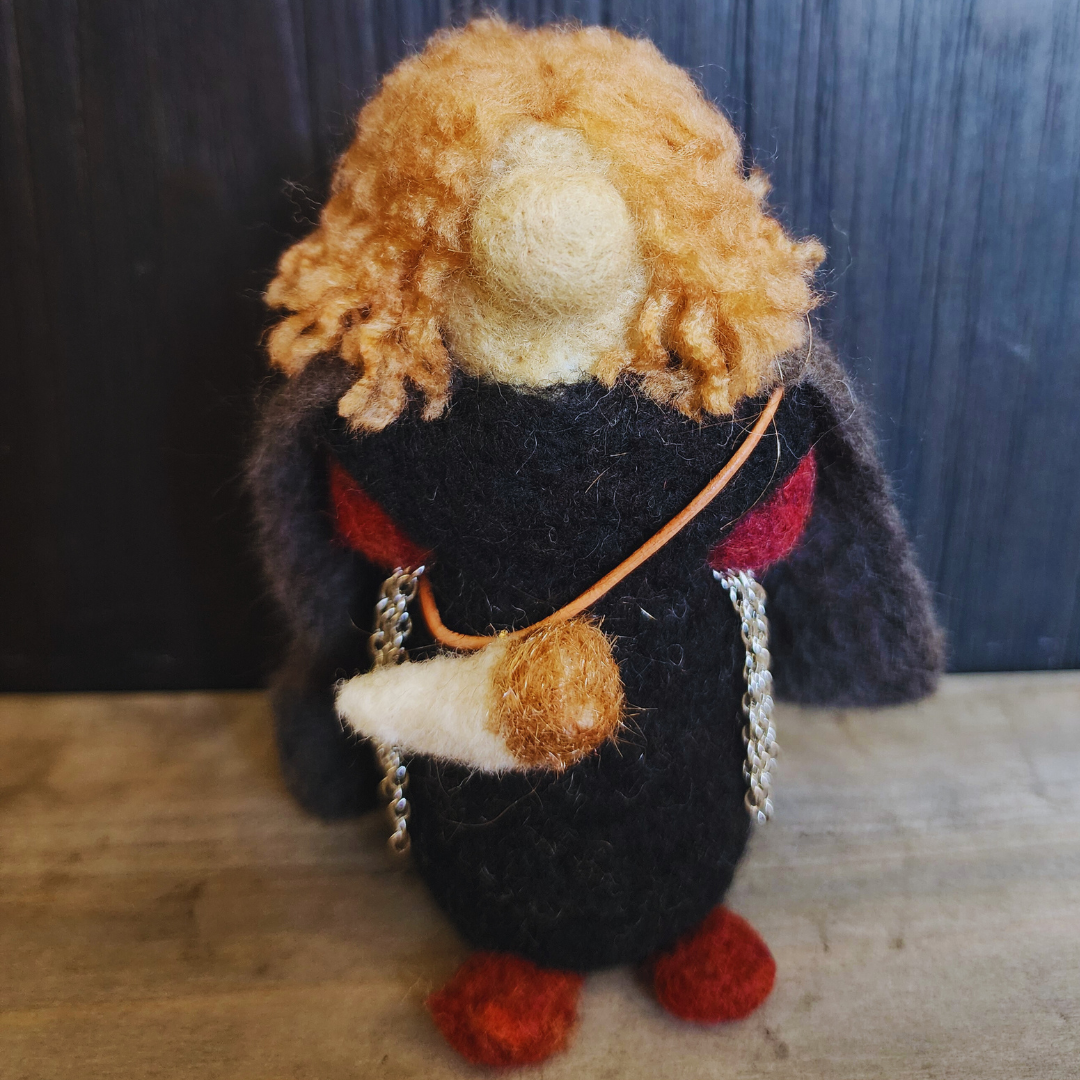 Close-up of a needle-felted Boromir figure with blonde hair and a black outfit, wearing the Horn of Gondor across his chest.