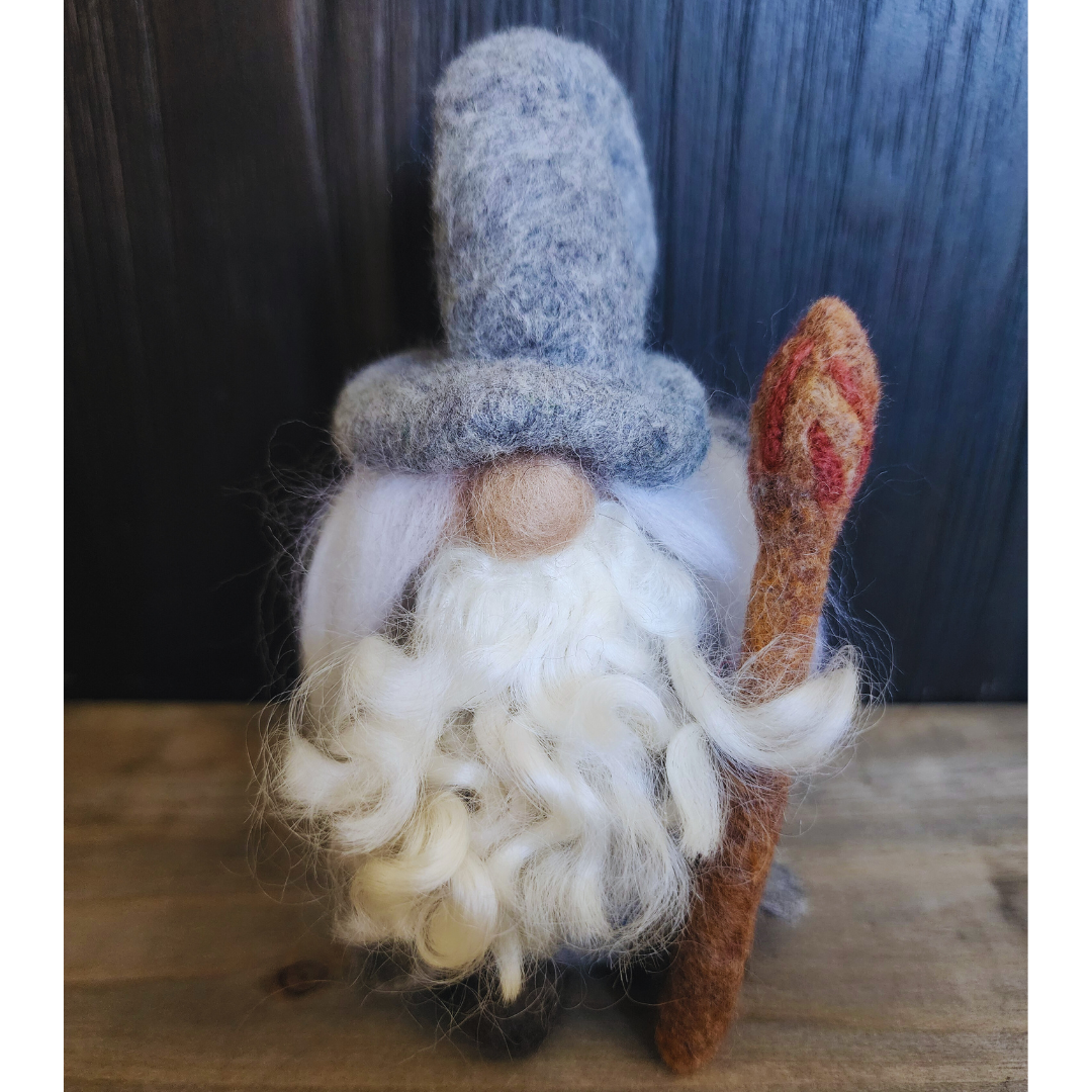 Front view of a needle-felted Gandalf the Grey with a tall grey hat, long white beard, and a brown staff.